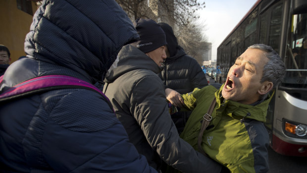 Plainclothes security officers take away a supporter of Chinese human rights lawyer Wang Quanzhang near the Secondary Intermediate People's Court of Tianjin.