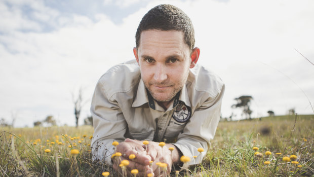 Ecologist with ACT Parks and Conservation Dr Brett Howland examines the Scaly Buttons at the Mulanggari grasslands in Gungahlin.