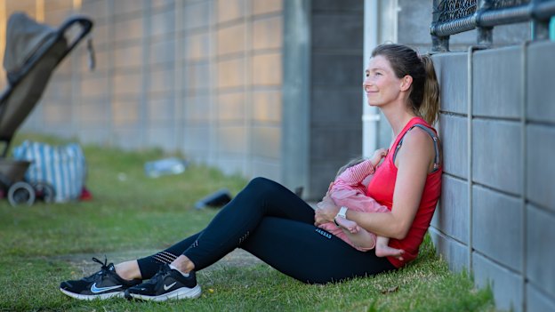 Grace Preuss takes a minute to breastfeed her daughter at footy training.