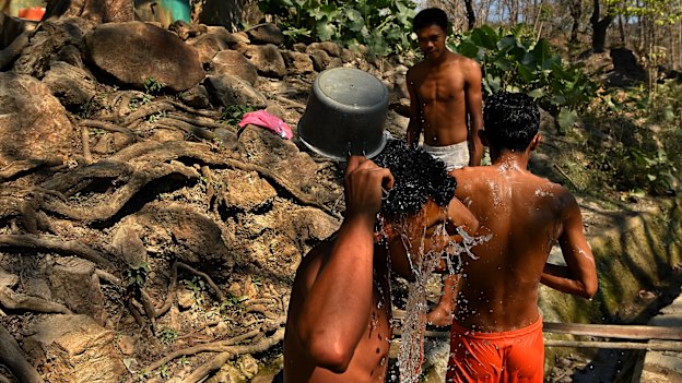 A group of men wash from a water point on the road entering Balibo, 50 years on from the invasion.
