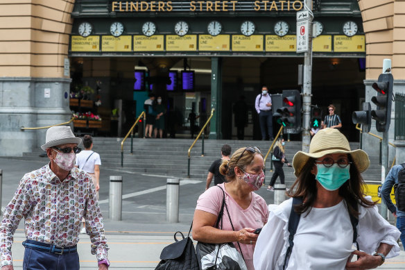 People wearing masks walk past Flinders Street Station on Thursday.