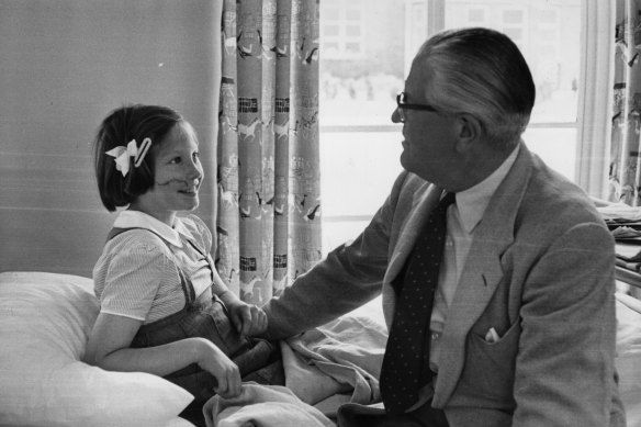 Plastic surgeon Sir Archibald McIndoe chats to a young patient at the Queen Victoria Hospital in East Grinstead, Sussex.