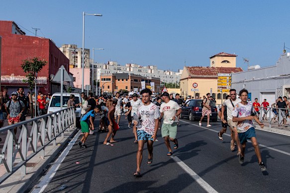 Migrants from Morocco run from Spanish police officers.