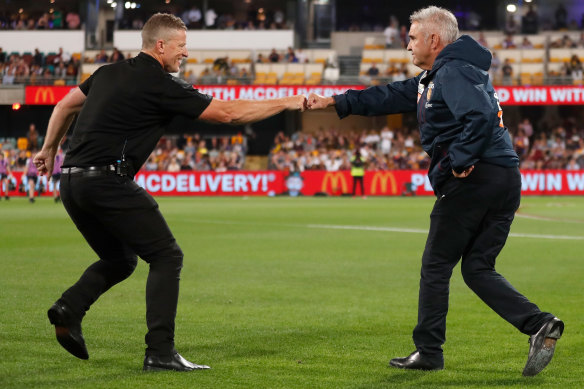 Tigers coach Damien Hardwick and Lions counterpart Chris Fagan bump fists at the Gabba.