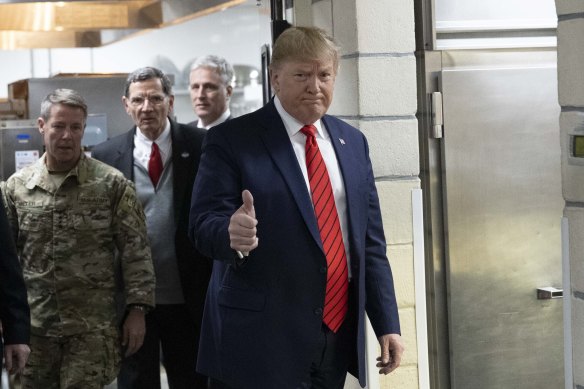 President Donald Trump gives the thumbs up as he prepares to serve dinner during a surprise Thanksgiving Day visit to the troops.