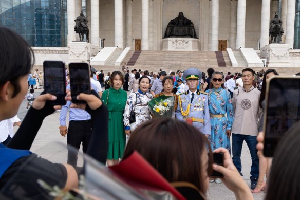 Bir grup Moğol, Hükümet Konağı önünde aile fotoğrafı çektiriyor.