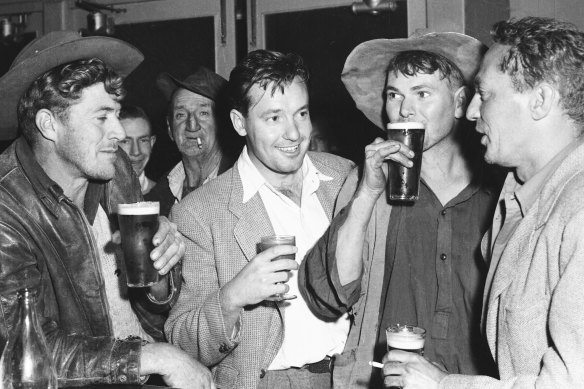 Australian actors Peter Finch (right) and Charles Bud Tingwell drink with locals in a Coonabarabran hotel during the making of the film The Shiralee on 16 August 1956.