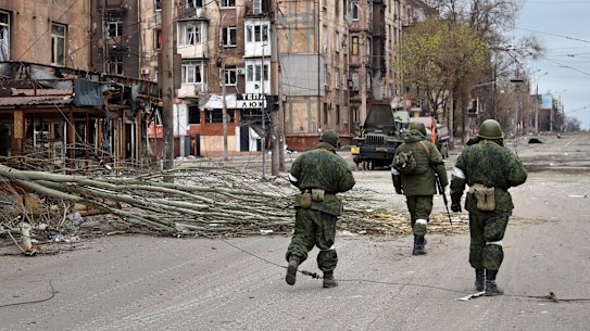 Servicemen of the militia from the Donetsk People’s Republic walk past damaged apartment buildings near the Mariupol plant.