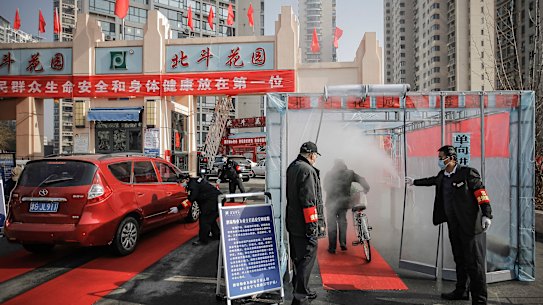 A cyclist walks through disinfectant spray in northern China.