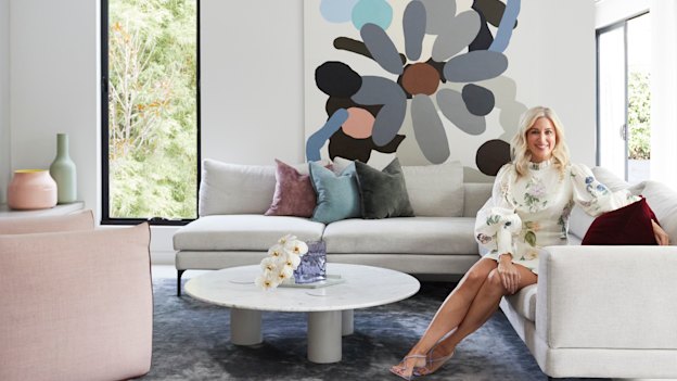 Aimee in the lounge room, which opens to an al fresco entertaining area. The large artwork is by Kirra Jamison and the sofa is from King Living.