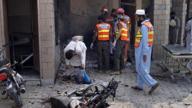 Pakistani security officials and rescue workers gather at the site of a bombing on an entrance of a hospital in Dera Ismail Khan on Sunday.