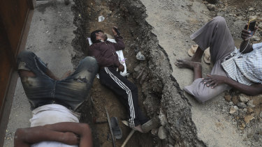 A labourer watches a movie on his mobile phone as he takes a break with others as they repair a road in Mumbai last week.