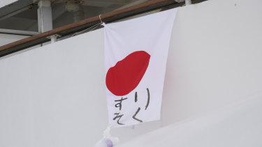 A Japanese flag with the message "Lack Medicine" written on it hangs from the Diamond Princess cruise.
