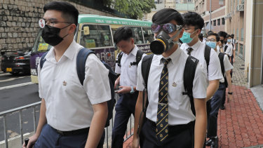 Coming as they are: students wear gas masks while dressed in their formal white school uniforms.