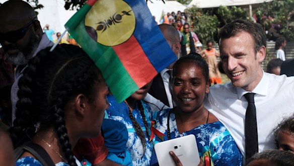 French President Emmanuel Macron, right, meets residents, one with the independence Kanak flag in her hair.