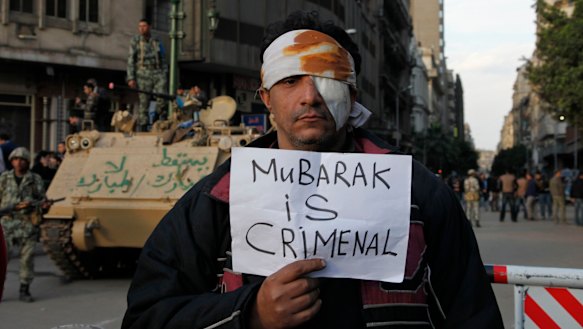 A wounded Cairo demonstrator carries a poster during the Arab Spring uprising.