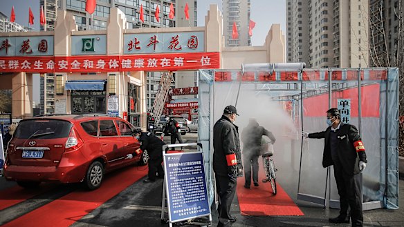 A cyclist walks through disinfectant spray in northern China.