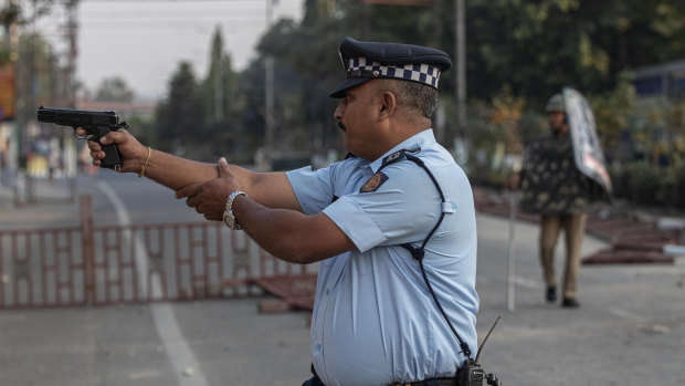 An Indian police officer aims his gun before firing at stone throwing protesters in Gauhati. No one was hurt in that firing.