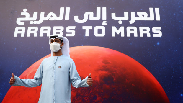 A man poses for a picture in front of a promotional poster in Dubai, United Arab Emirates.