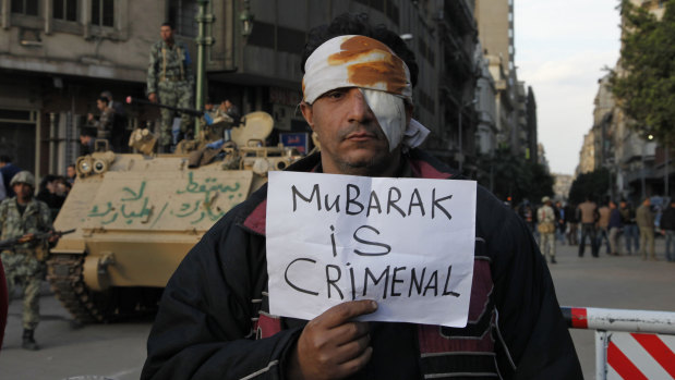 A wounded Cairo demonstrator carries a poster during the Arab Spring uprising.