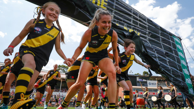 Staying positive: Katie Brennan and the Richmond AFLW mascots run through the banner before the start of the game against the Kangaroos at Ikon Park in Melbourne.