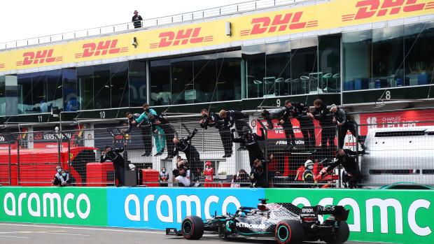 Mercedes GP team members celebrate on the pitwall as Lewis Hamilton crosses the finishing line.