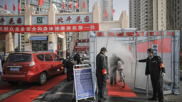 A cyclist walks through disinfectant spray in northern China.