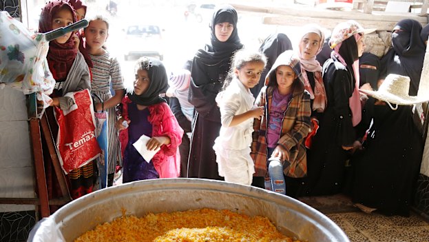 People wait for food aid in Yemen during a truce in fighting in April.