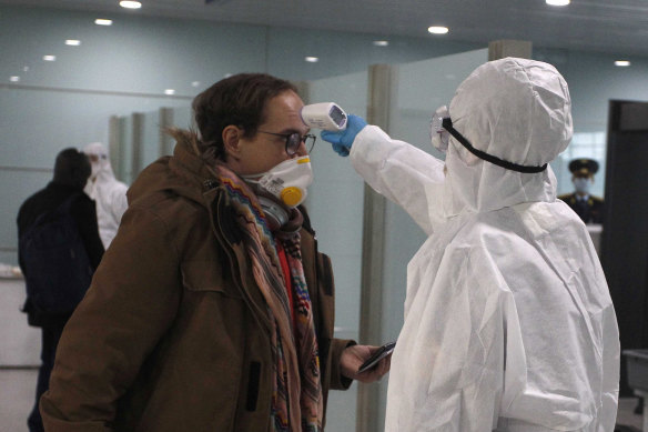 A passenger wearing a mask as a precaution against coronavirus has his temperature checked before boarding a flight to Vladivostok, Russia, at the Pyongyang International Airport in North Korea.
