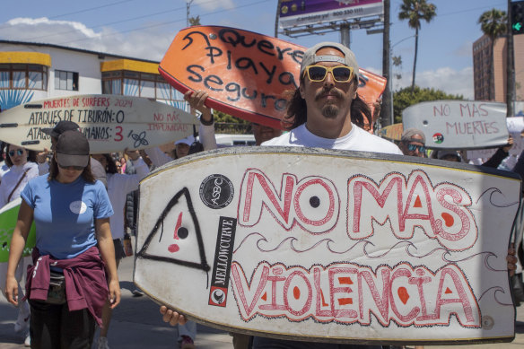 A demonstrator holding a bodyboard written in Spanish “No more violence” protests the death of the Robinson brothers and their American friend in Ensenada, Mexico.