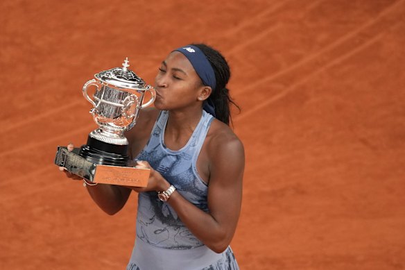 Gauff celebrates as she holds the trophy.