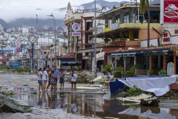Residents look at debris in the streets after hurricane Otis hit Acapulco in Acapulco, Mexico.