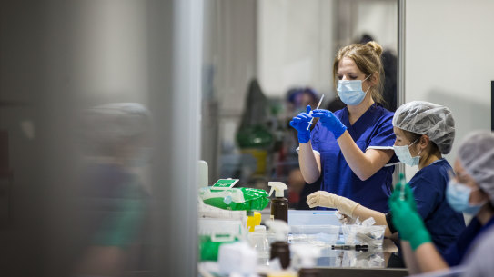 Staff are seen preparing vaccine doses inside the Melbourne Exhibition Centre COVID-19 Vaccination Centre.