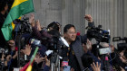 Bolivian President Luis Arce raises a clenched fist surrounded by supporters and media, outside the government palace in La Paz, Bolivia.