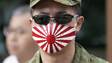 A man at at the Yasukuni Shrine in Tokyo wears a mask with a design of Japan's rising sun flag.