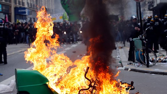French riot police stand next a burning rubbish bin during the protests in Paris.