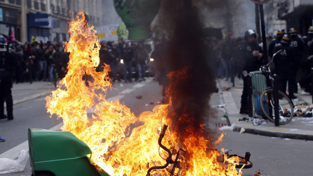 French riot police stand next a burning rubbish bin during the protests in Paris.