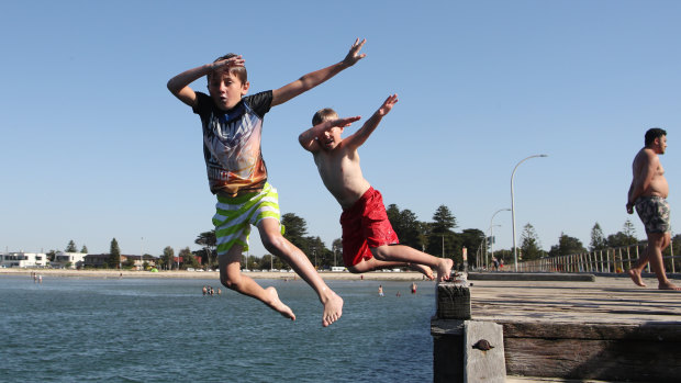 Children jump  into the water off Altona pier on Friday.