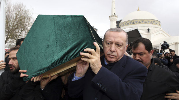 Turkish President Recep Tayyip Erdogan, centre, carries a coffin as he joins hundreds of mourners at the funeral of nine members of one family killed in the collapsed apartment building in Istanbul.