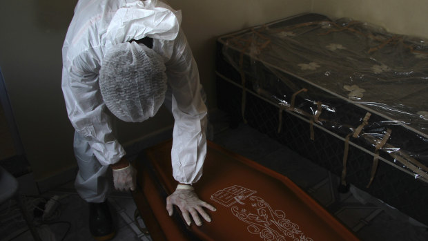 A public funeral service worker helps to remove the body of a man who died from complications related to COVID-19 in his home, in Manaus, Amazonas state, Brazil.