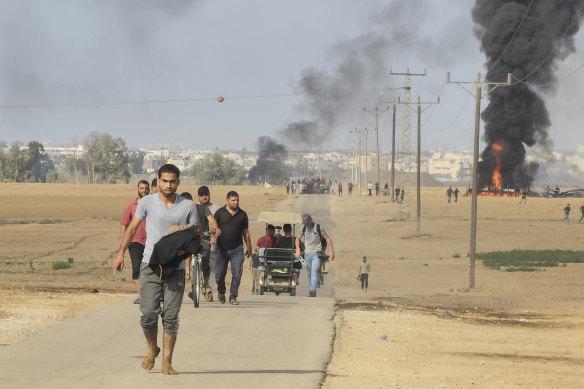 Palestinians walk away from the kibbutz of Kfar Azza, Israel, near the fence with the Gaza Strip.