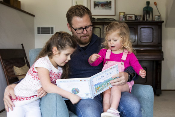 Andrew Kennedy at home, reading to daughters Isla, 5, and Hope, 2.