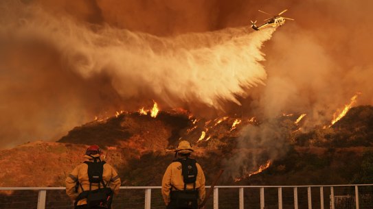 Firefighters watch as water is dropped on the Palisades Fire in Mandeville Canyon.