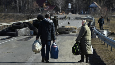 Local residents walk towards their home over a destroyed bridge laid with anti tank mines, east of Kyiv, Ukraine.