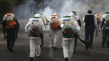 Firefighters disinfect a square against the new coronavirus, in western Tehran, Iran.