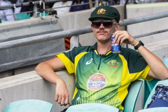 A fan in the SCG stands enjoying a cold beer. 