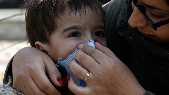 A woman helps her boy to put on a mask in central Tehran, Iran.