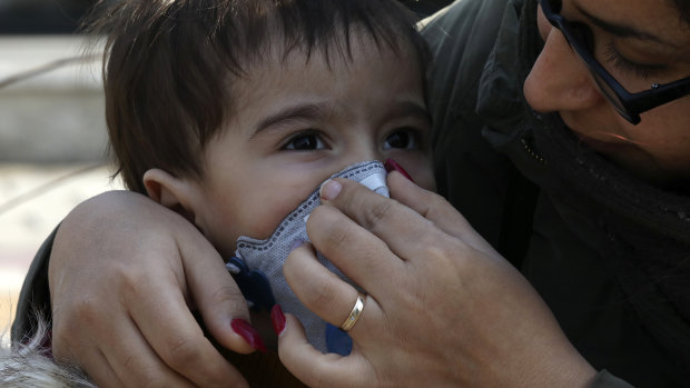 A woman helps her boy to put on a mask in central Tehran, Iran.