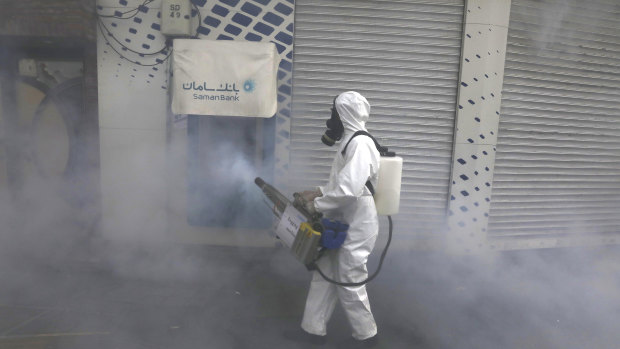 A firefighter disinfects an ATM in Tehran. Several Iranian top officials, MPs and cabinet ministers have tested positive for COVID-19.