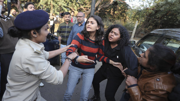 Policewomen detain youth during a protest against a new citizenship law in Ahmadabad, India on Monday.